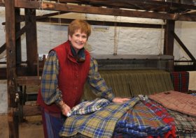 Rachel Hammerton with an array of kilts infront associated with 1920s Armstrong Loom